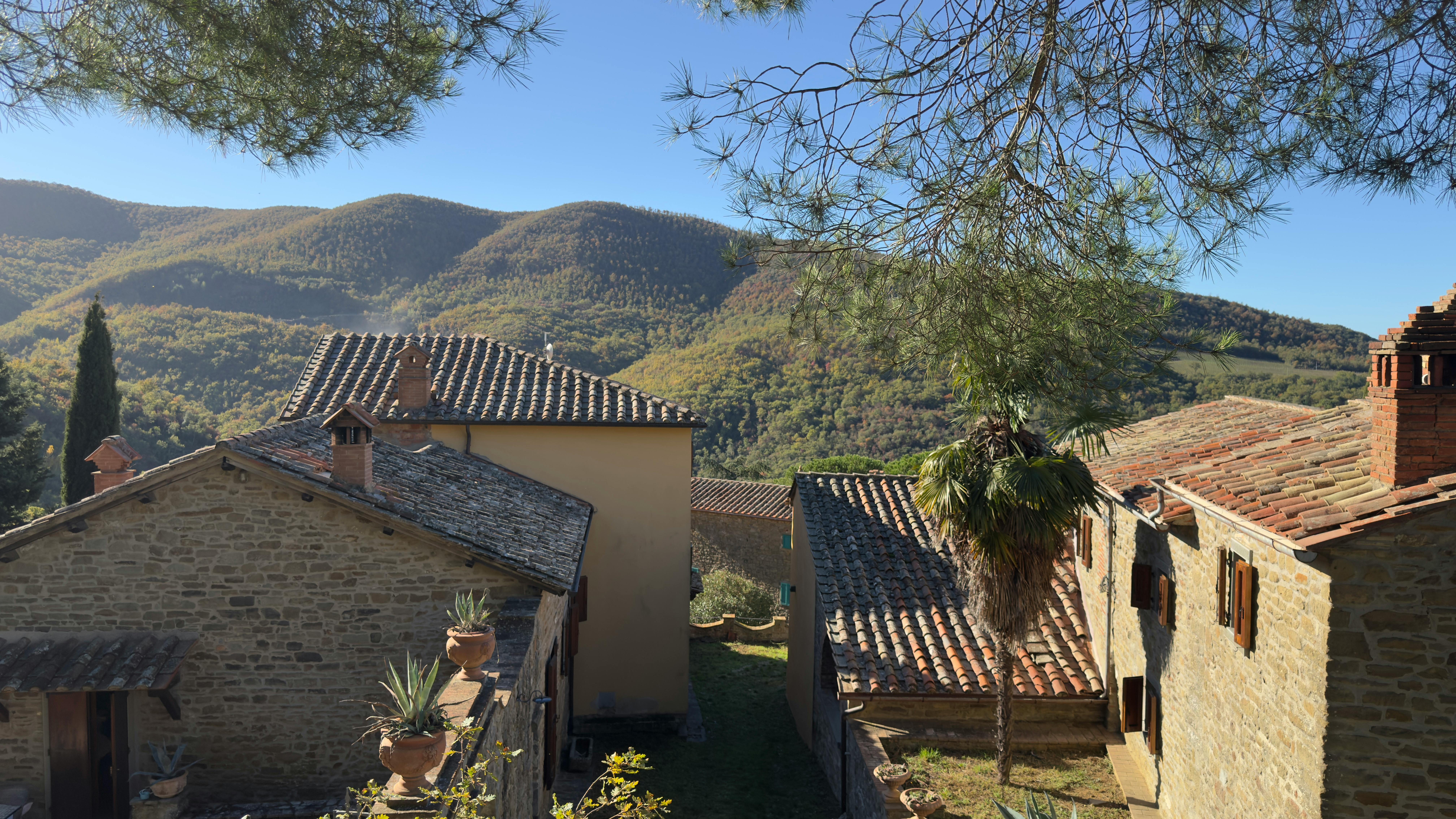Rustic village in Tuscany with hillside backdrop under clear blue sky.